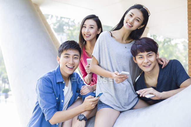 Chinese friends holding smartphones and looking in camera — Stock Photo