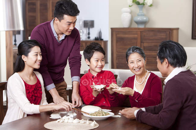 Cheerful multi-generation family making Chinese dumplings — Stock Photo