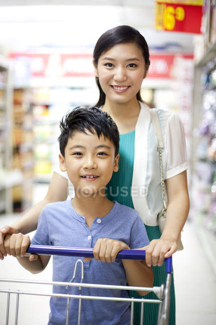 Chinese mother and son with shopping cart in supermarket — Stock Photo