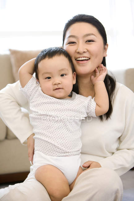 Chinesin sitzt und hält Baby auf Schoß — Stockfoto
