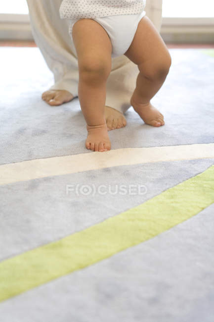 Pernas infantis no tapete com padrão forrado — Fotografia de Stock