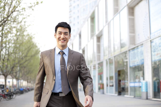 Homme d'affaires chinois confiant marchant dans le centre-ville — Photo de stock