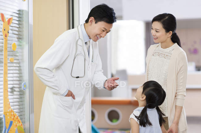 Médico chino hablando con chica en el hospital - foto de stock