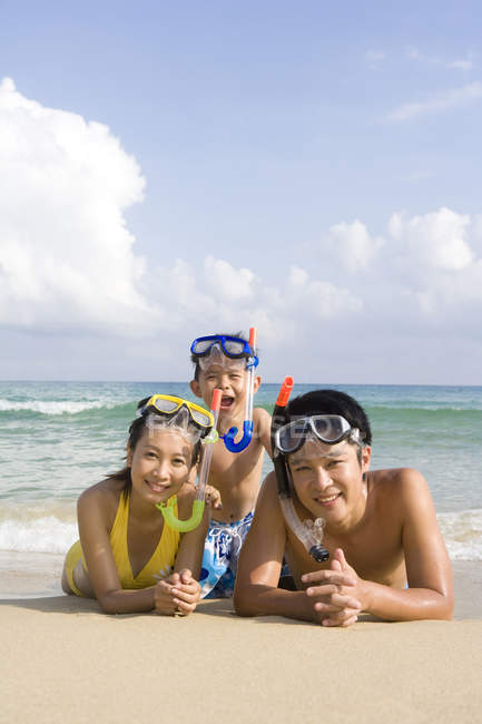 Junge Familie mit Tauchermasken am Strand liegend — Stockfoto