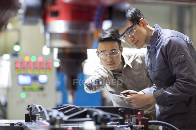 Chinese engineers checking machine in factory — Stock Photo