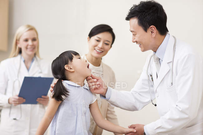Chinese doctor examining girl mouth — Stock Photo