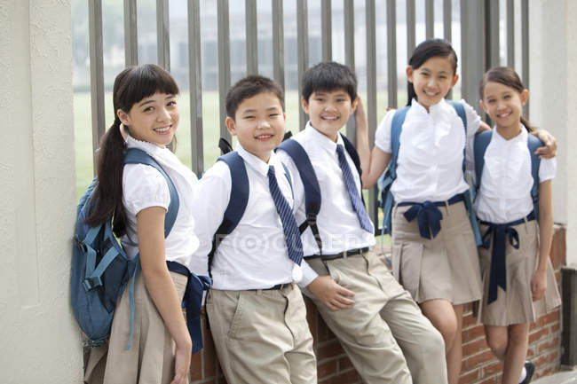 Chinese schoolchildren in school uniform leaning against fence — Stock Photo