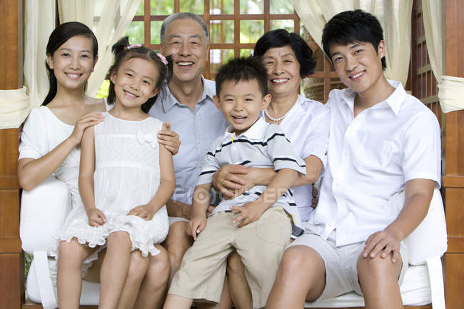 Портрет китайской семьи с братьями и сёстрами, сидящими на скамейке в отпуске — стоковое фото