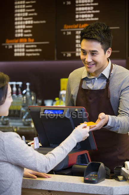 Chinese female customer paying by credit card in coffee shop — Stock Photo