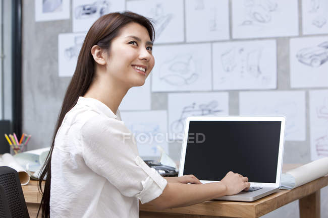 Китаянка-дизайнер с ноутбуком в офисе — стоковое фото