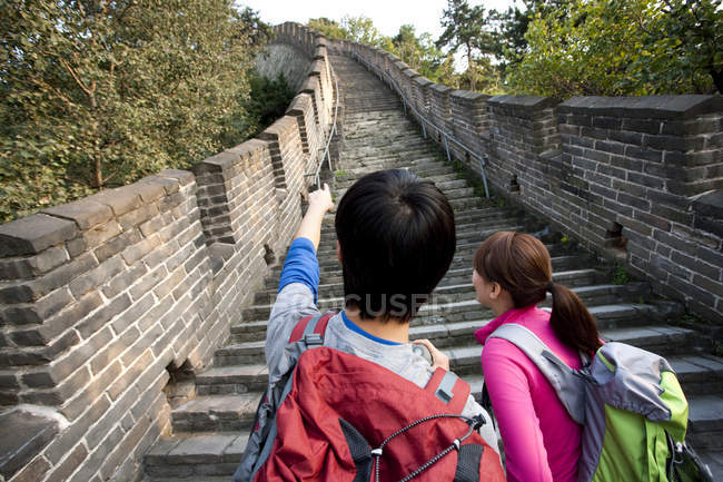 Вид сзади на пару туристов, указывающих на Великую стену — стоковое фото