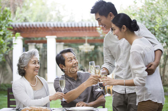 Happy Chinese family celebrating with champagne outdoors — Stock Photo