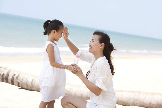 Madre cinese che applica la crema solare sulla figlia — Foto stock
