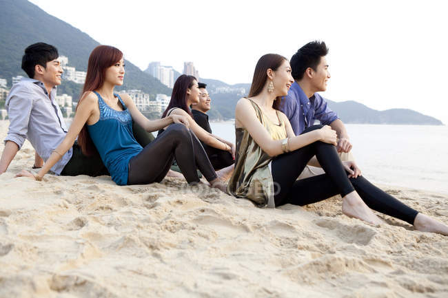 Grupo de amigos chinos sentados en la playa de Repulse Bay, Hong Kong - foto de stock