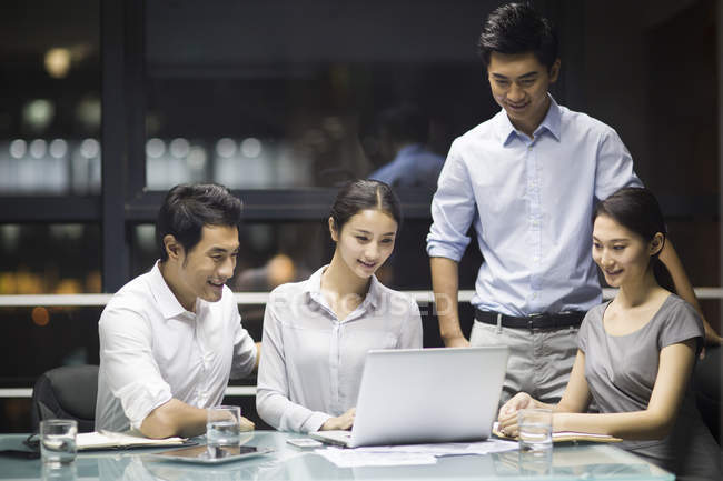Gente de negocios chinos utilizando el ordenador portátil en reunión - foto de stock