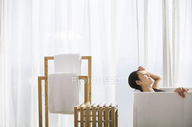 Chinese woman relaxing in bathtub — Stock Photo