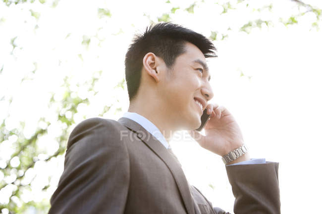 Китайський бізнесмен, розмовляємо по телефону на відкритому повітрі — стокове фото