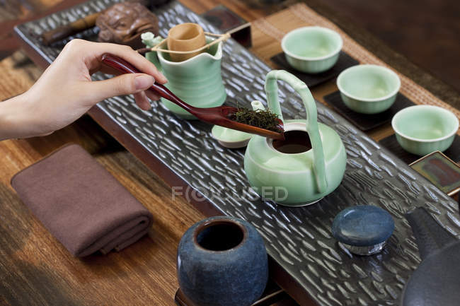 Close-up de mão feminina colocando folhas de chá em bule — Fotografia de Stock