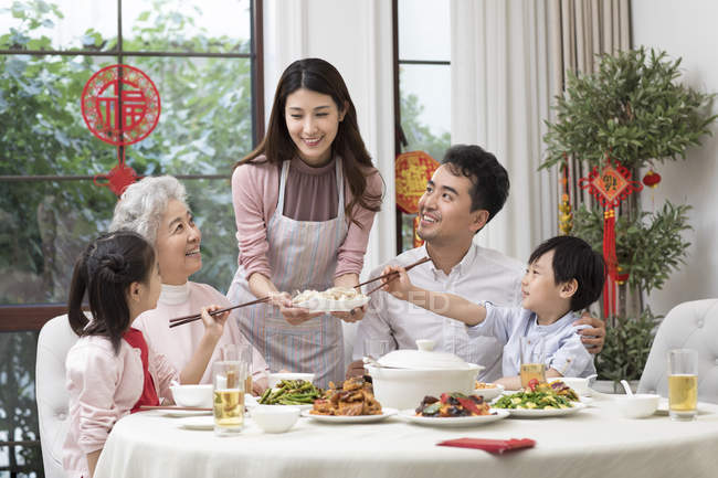 Mujer joven sirviendo la cena de Año Nuevo chino a la familia - foto de stock