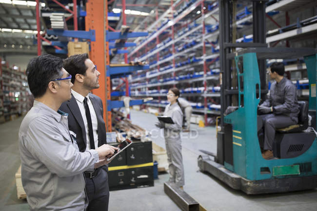 Businessman and engineer talking at industrial factory — Stock Photo