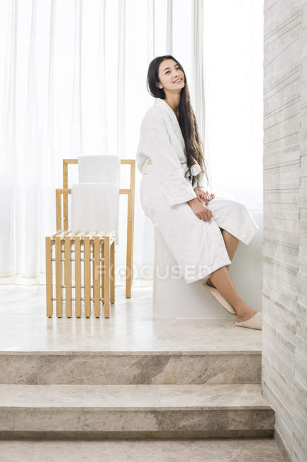 Китайська жінка, що сидить у ванній кімнаті і, дивлячись в камери — стокове фото