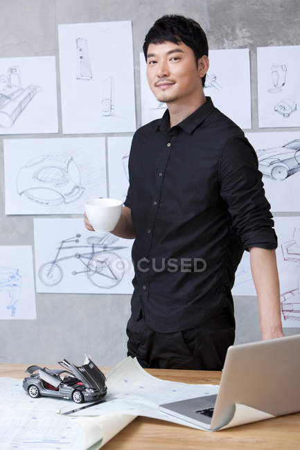 Автодизайнер с чашкой кофе в офисе — стоковое фото