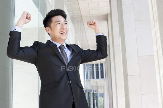 Chinese businessman cheering with arms raised — Stock Photo