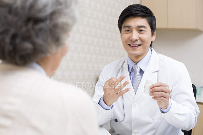 Médico chino explicando la dosis de medicamento al paciente - foto de stock