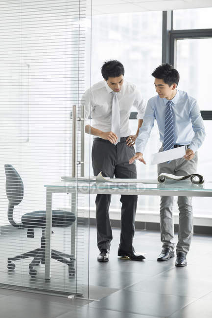 Chinese businessmen talking in office interior — Stock Photo