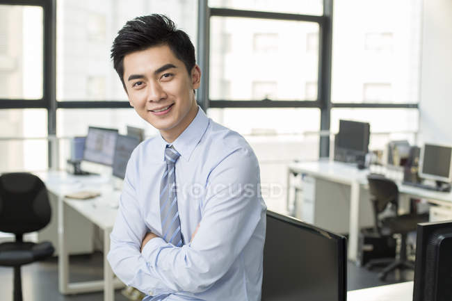Homme d'affaires chinois debout avec les bras croisés dans le bureau — Photo de stock