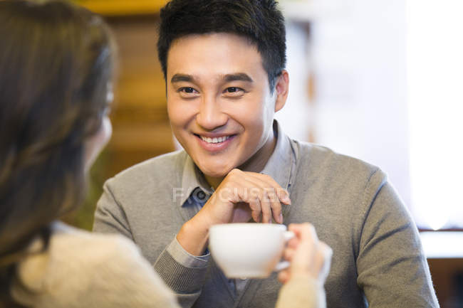 Chino pareja charlando en la cafetería con taza de café - foto de stock