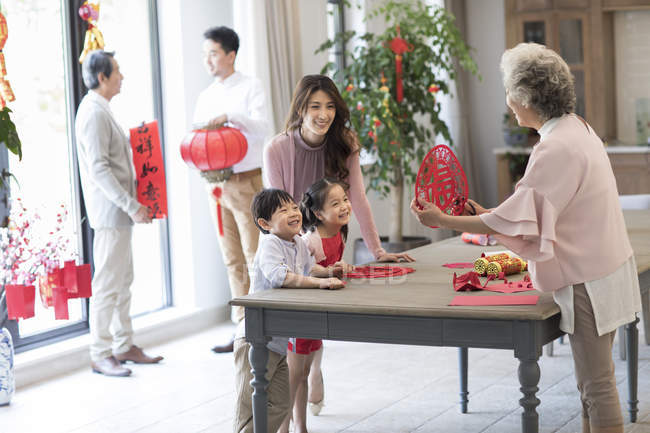 Abuela con los niños y la madre haciendo chino de Año Nuevo papel de corte - foto de stock