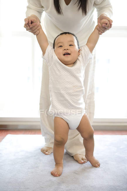 Chinese woman helping son walking in living room — Stock Photo