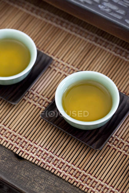 Крупный план чая в китайских чашках на бамбуковых листках — стоковое фото