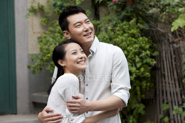 Chinese couple embracing and looking at view — Stock Photo