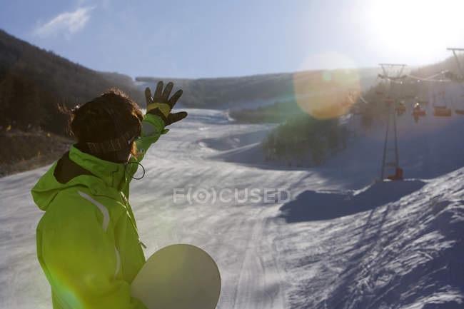 Hombre mirando a la vista de invierno con el brazo extendido - foto de stock