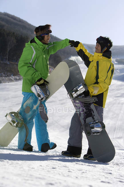Jeunes hommes avec des snowboards parlant à la station de ski — Photo de stock