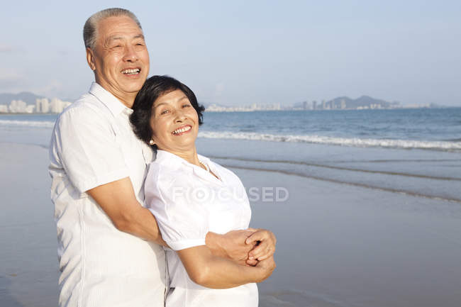 Chinesisch senior pärchen umarmen auf strand — Stockfoto