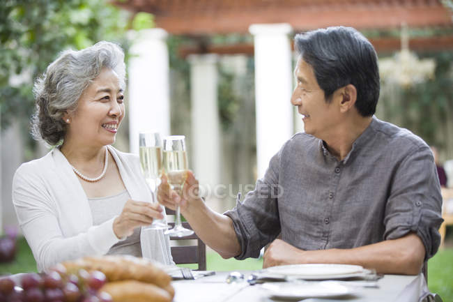 Senior pareja china tintineo flautas de champán - foto de stock