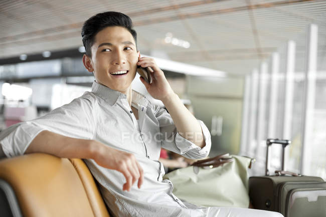 Chinese man talking on phone at airport building — Stock Photo