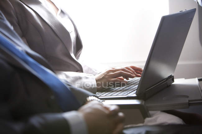 Pessoas de negócios que trabalham com laptop no avião, vista cortada — Fotografia de Stock