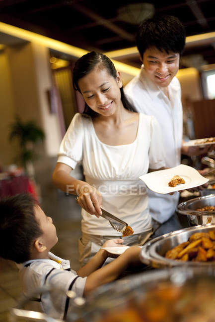 Chinese mother helping son at hotel buffet — Stock Photo