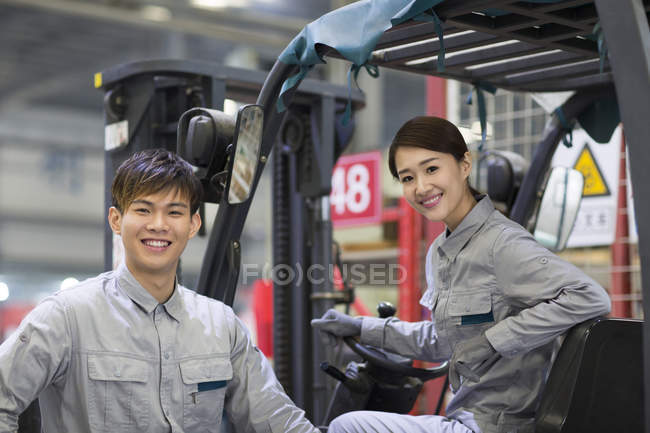 Китайские рабочие позируют с вилочными погрузчиками на заводе — стоковое фото