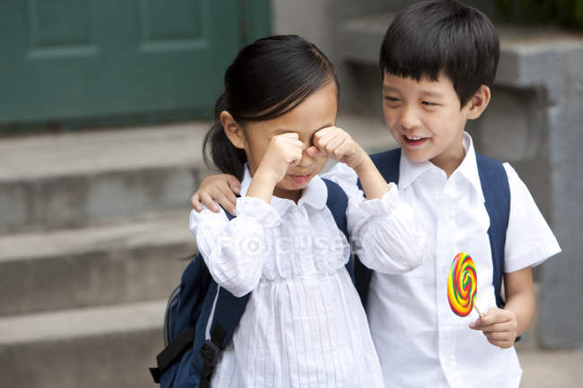 Chinese boy consoling crying girl with lollipop — Stock Photo