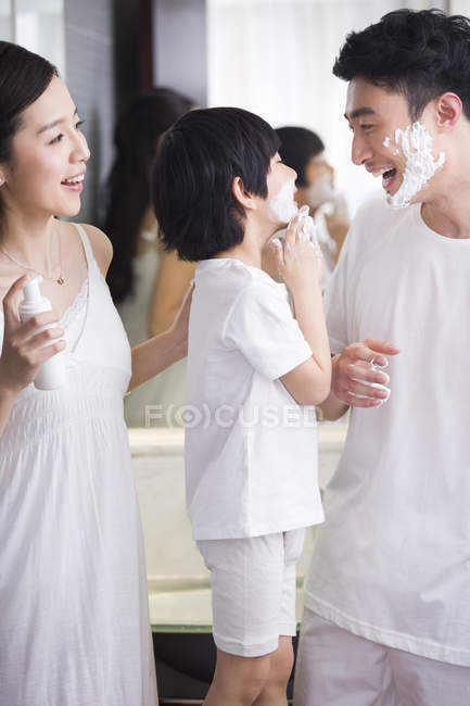Chinese father and son in bathroom with shaving cream on chins — Stock Photo