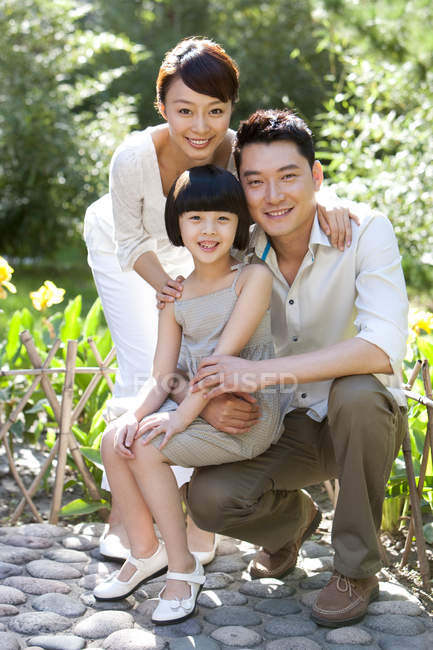 Retrato de familia china con hija en el jardín - foto de stock