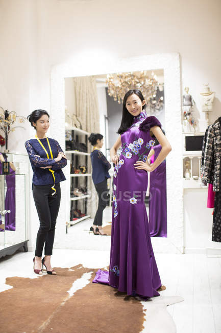 Designer de moda chinesa examinando vestido no cliente — Fotografia de Stock