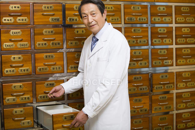 Medico cinese anziano in piedi con cassetto aperto — Foto stock