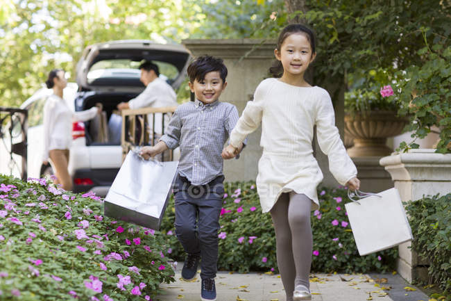 Chinese sibling with shopping bags walking in courtyard — Stock Photo
