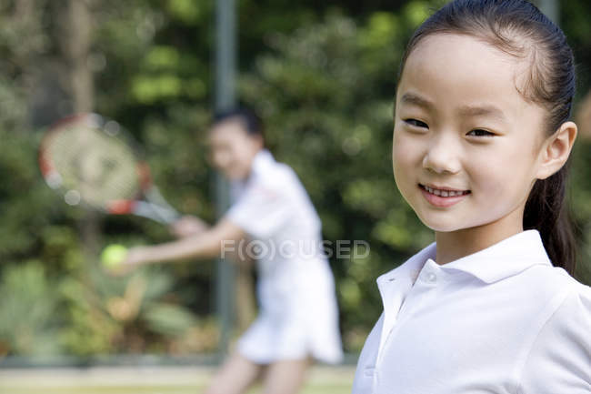 Chinesin auf Tennisplatz mit Mutter im Hintergrund — Stockfoto